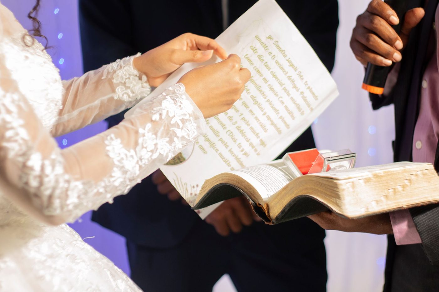 Bride in a white dress reading her wedding vows to her groom during an outdoor ceremony