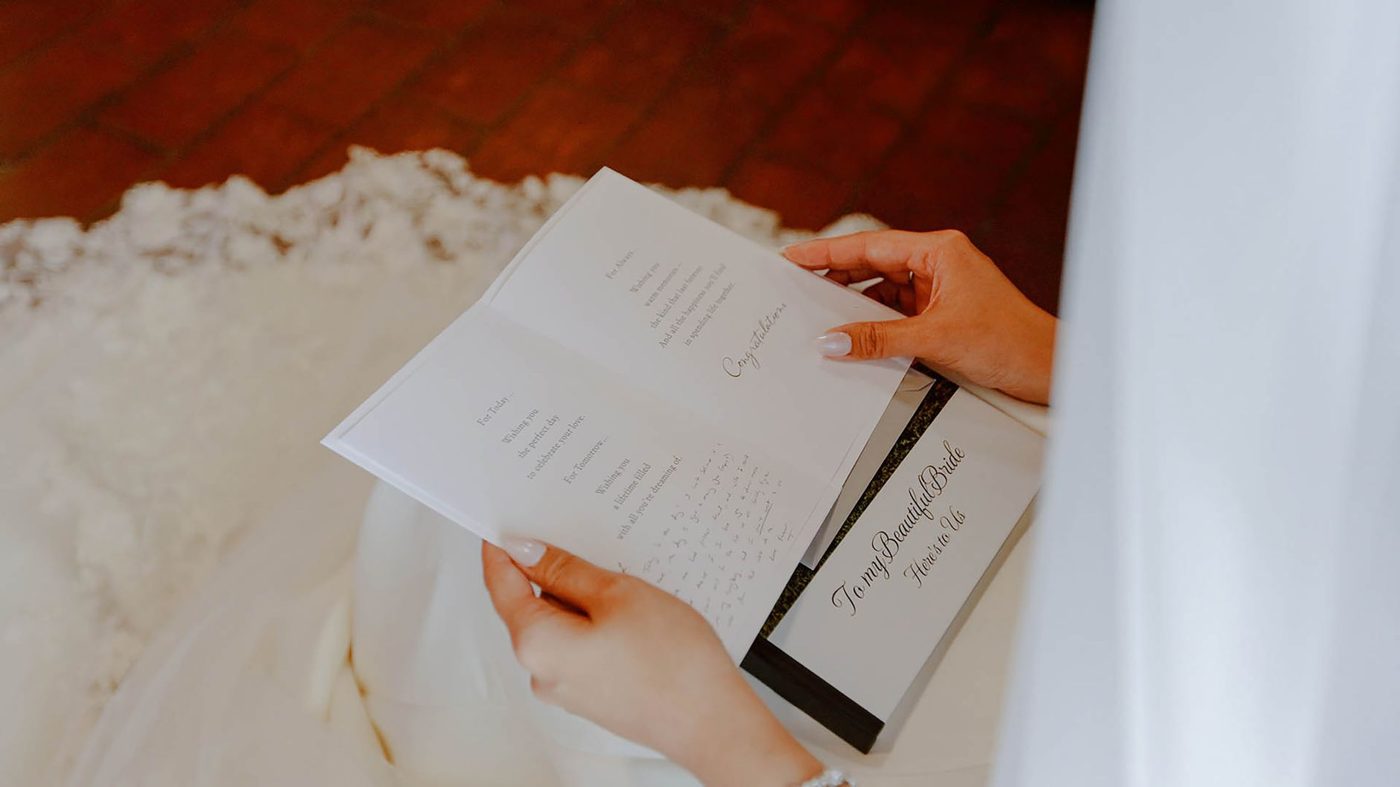 Bride reading her vows from a small card while holding hands with her groom at the altar