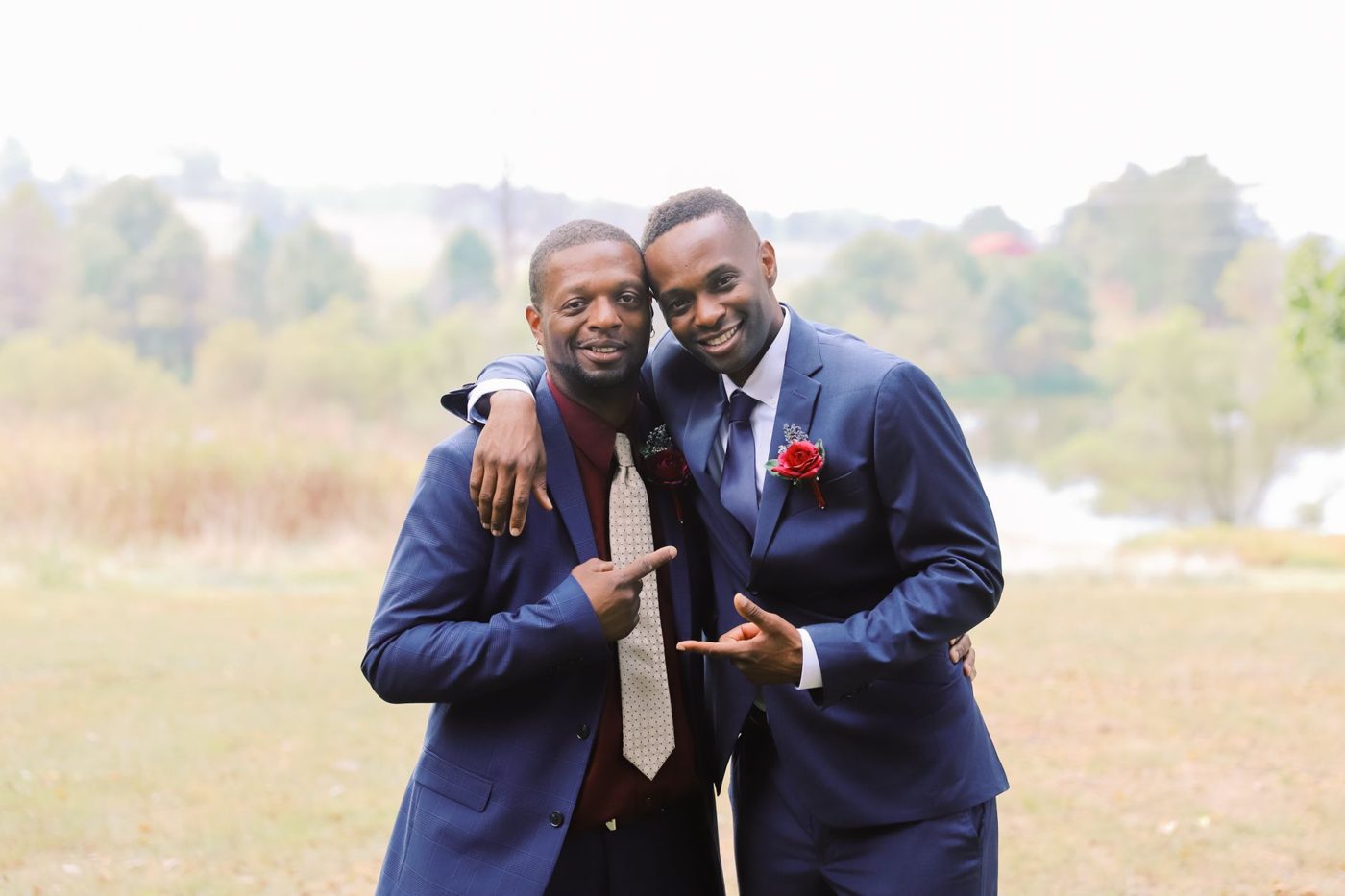 Two brothers in suits laughing together before a wedding ceremony