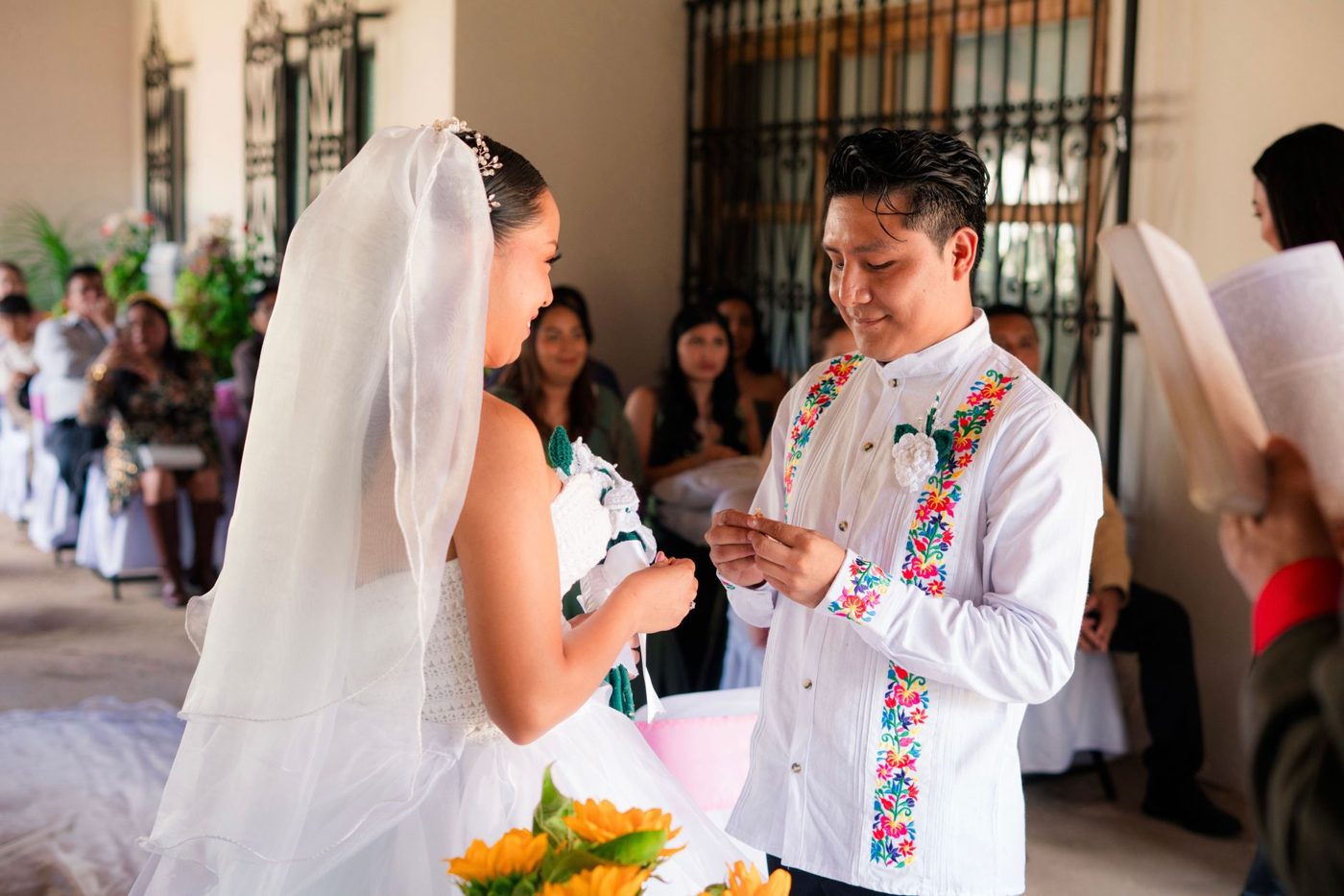 Groom reading his wedding vows to his bride during the ceremony while she smiles