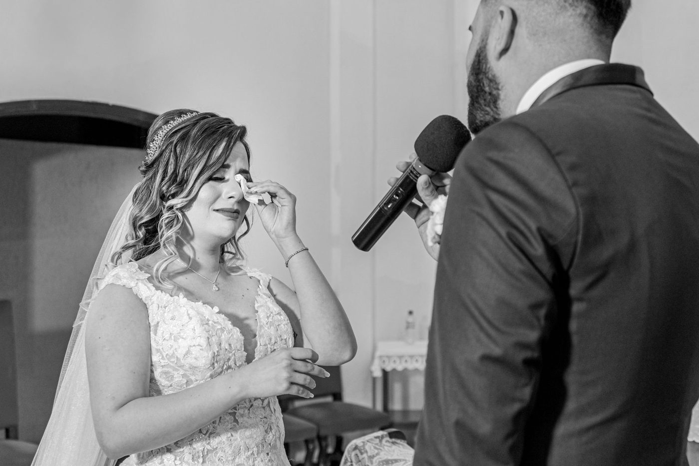 Bride smiling through tears as she reads her vows at the ceremony