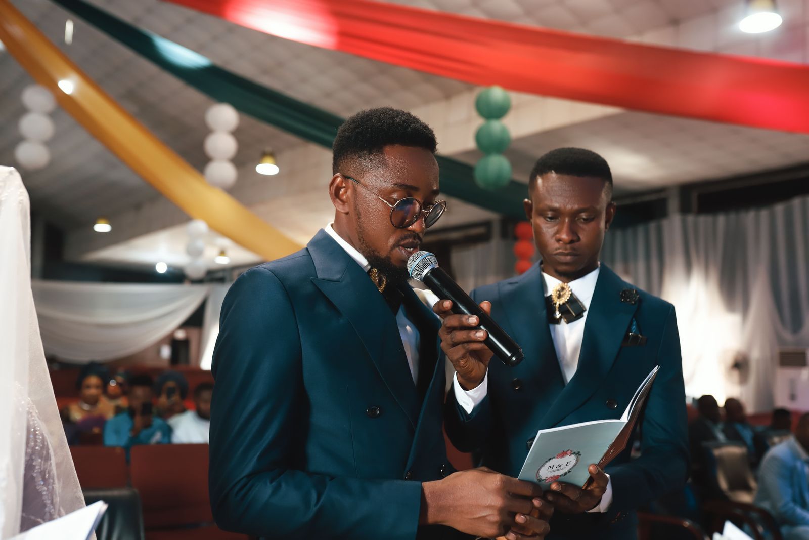 Two men in suits sharing a toast during a wedding ceremony