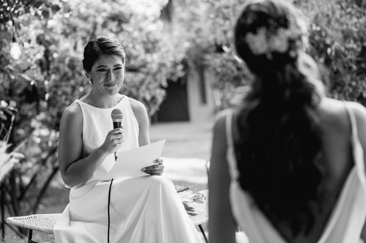 Bridesmaid and bride sharing an emotional moment during a wedding speech outdoors