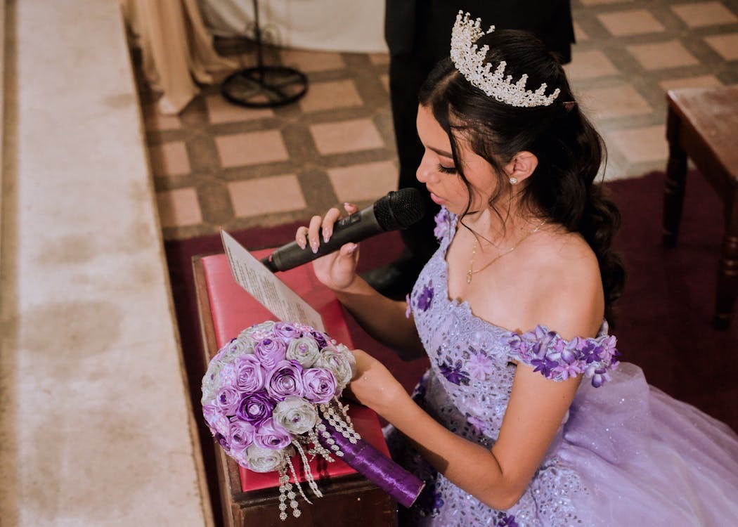 Young woman in a dress giving a speech at a wedding holding a bouquet