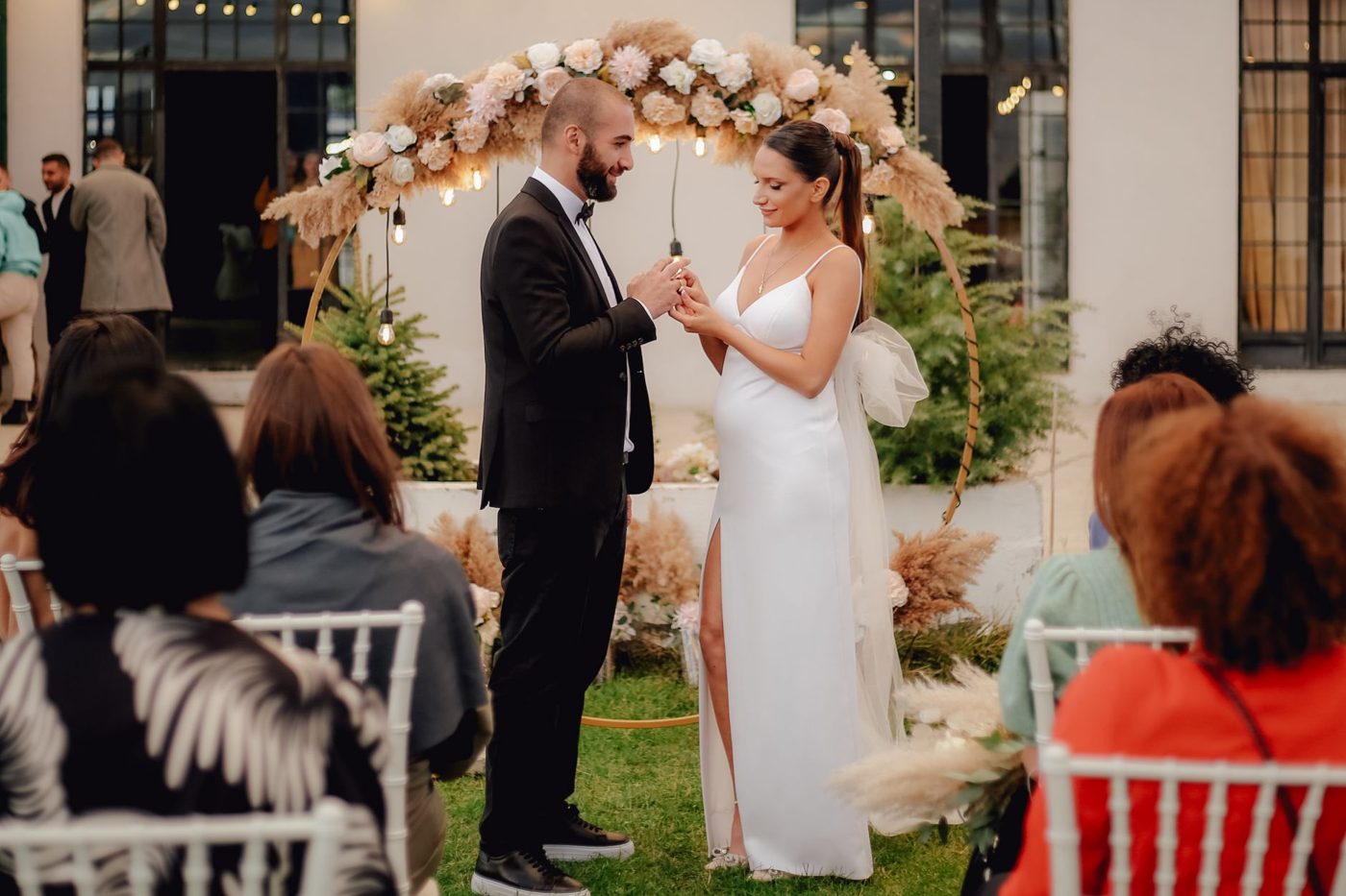Couple holding hands and exchanging vows in front of an officiant at an outdoor wedding ceremony