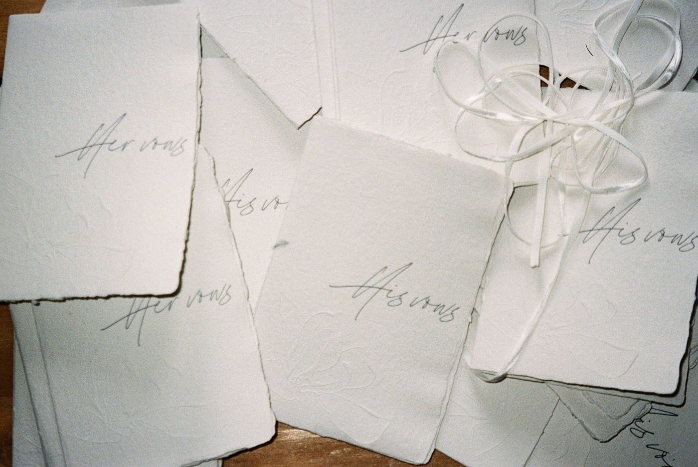 Handwritten wedding vows on cream paper next to a pen and a pair of wedding rings