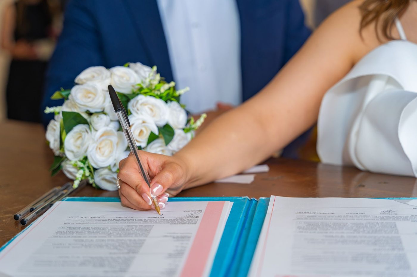 Handwritten wedding vows on paper next to a pen and a small bouquet