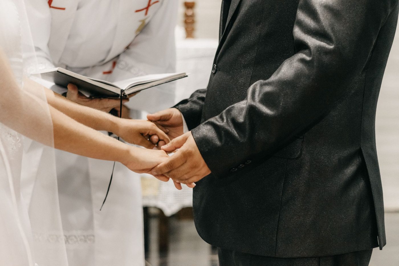 Bride and groom holding hands while exchanging vows at their ceremony