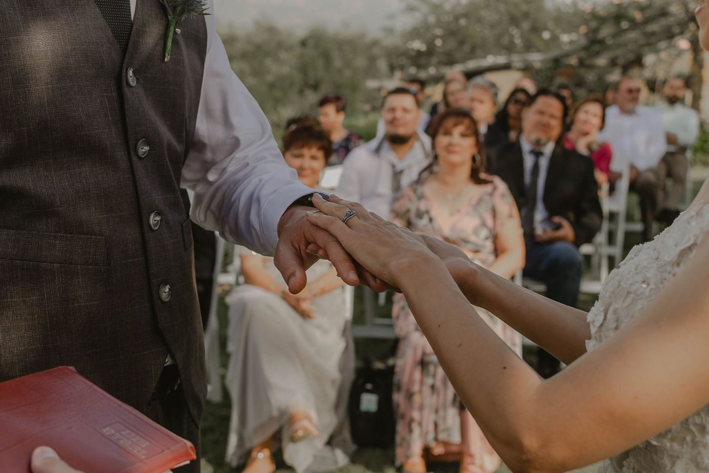 Couple holding hands and saying their vows to each other at an outdoor wedding ceremony
