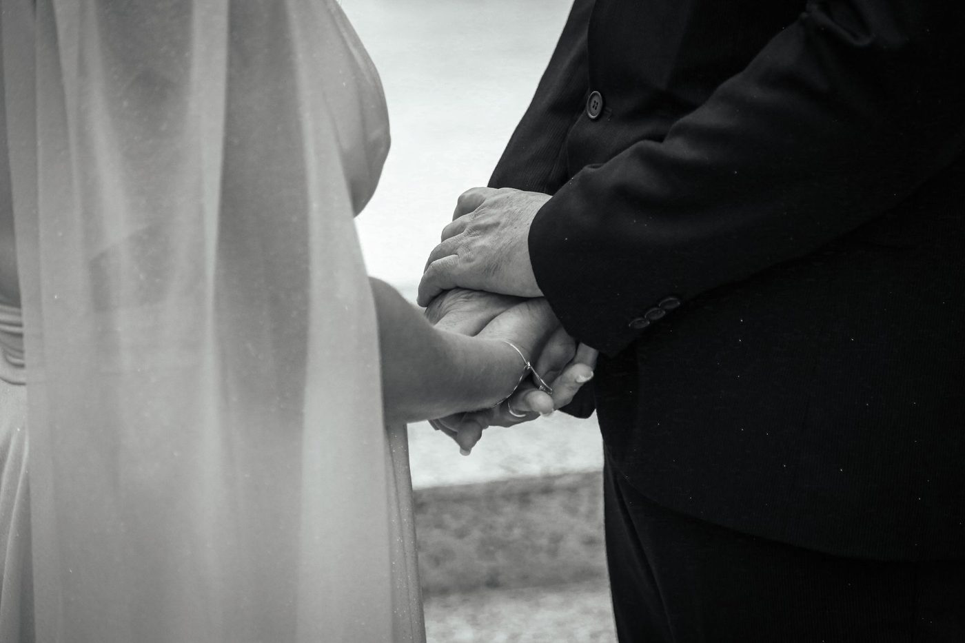 Bride and groom holding hands facing each other while an officiant speaks during their ceremony