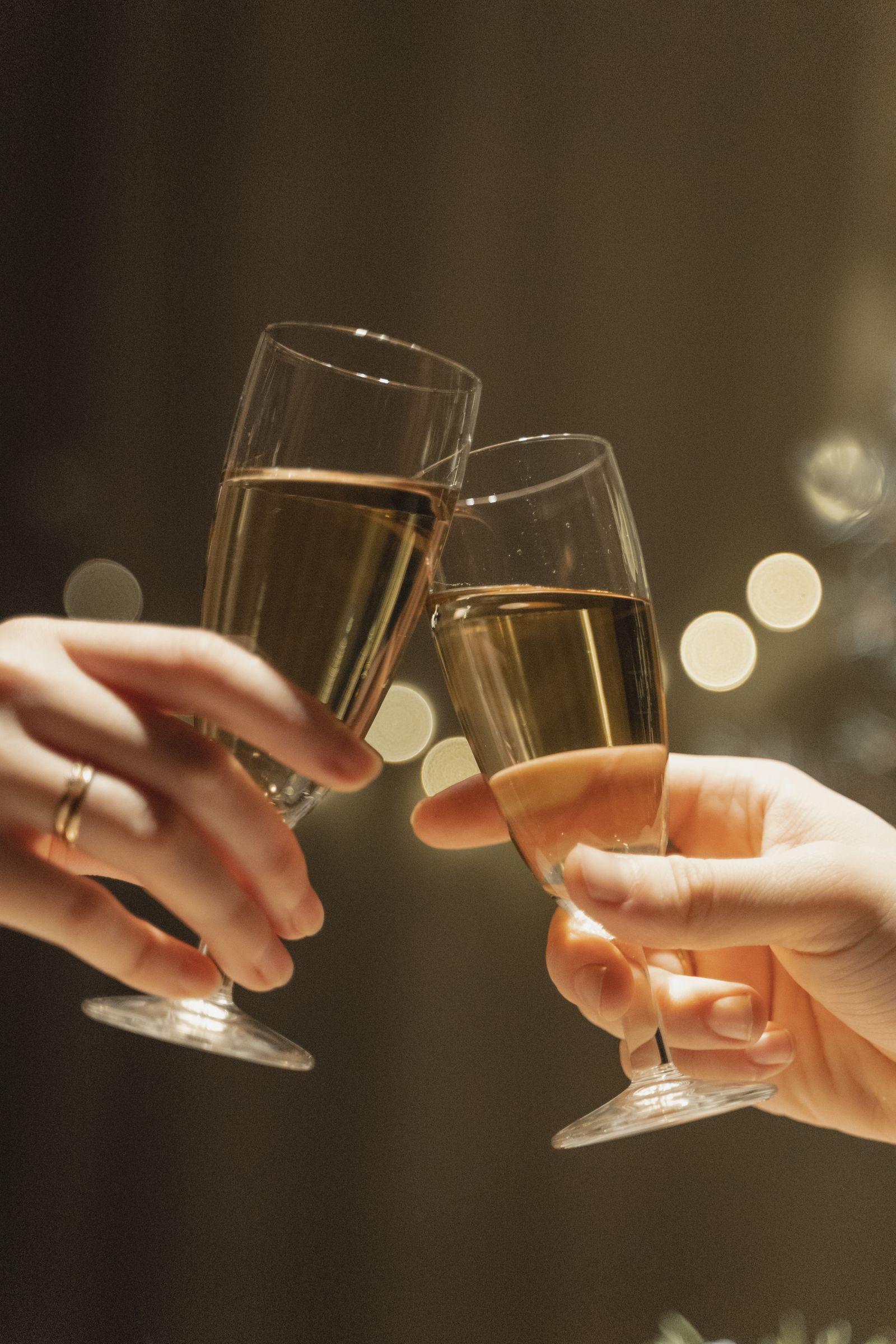 Close-up of two hands clinking champagne glasses in a celebratory toast