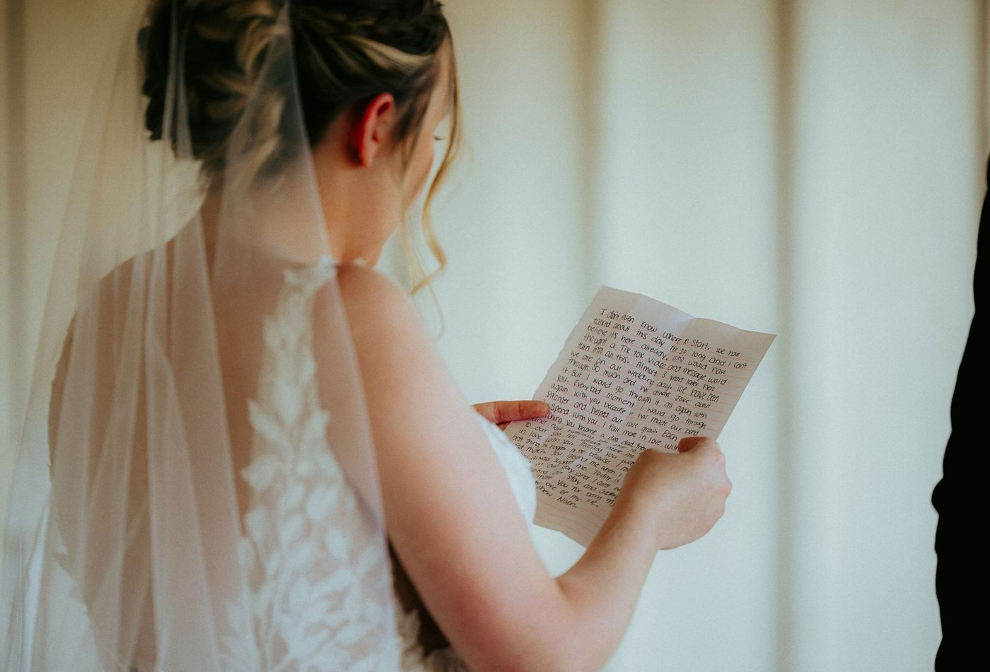Bride reading handwritten wedding vows from a card while holding a bouquet