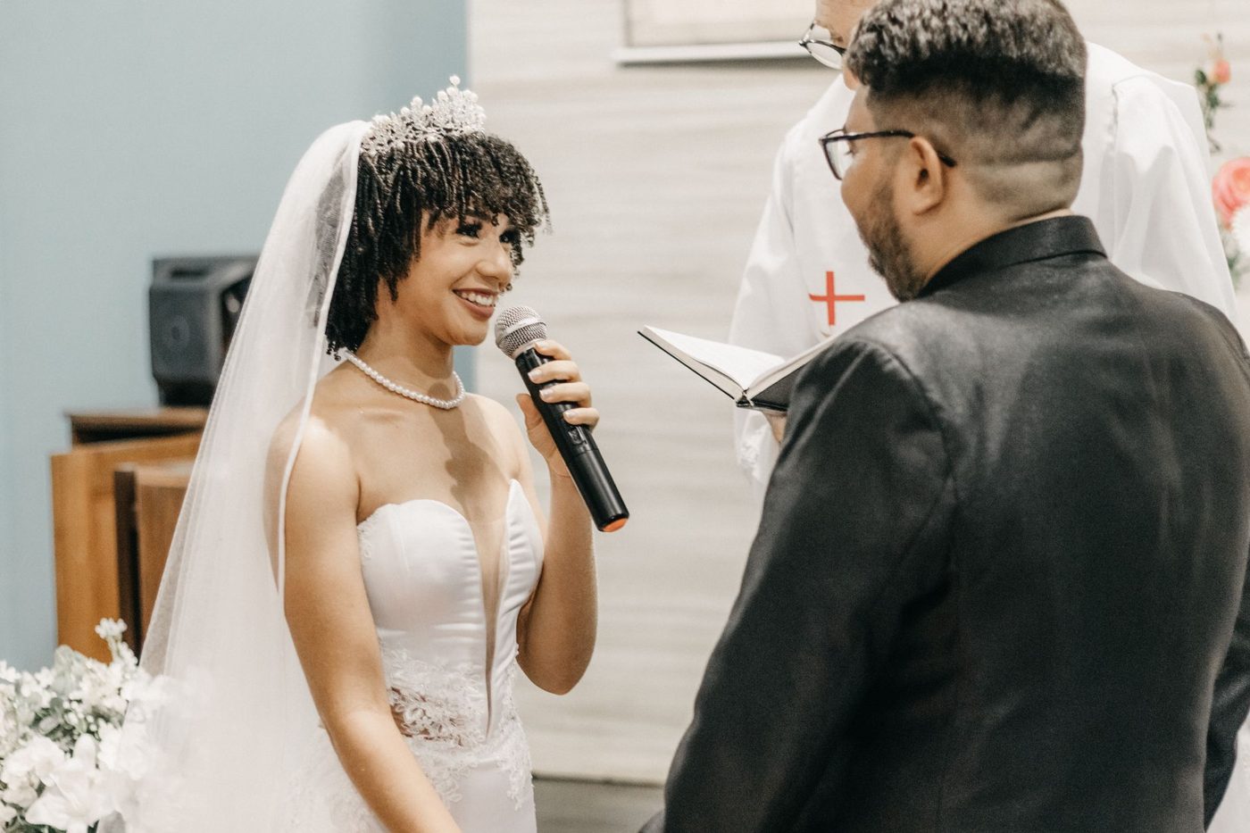 Groom reading his wedding vows to his bride while she smiles at him