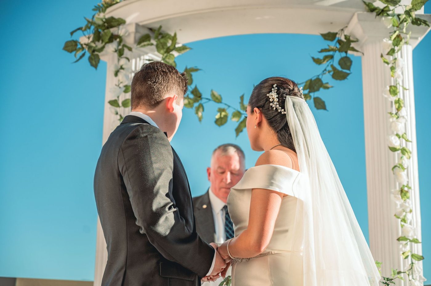 Bride laughing and wiping a tear while her partner reads vows at the ceremony